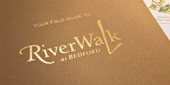 Detail photo of the RiverWalk at Bedford brochure cover with focus on the foil stamp logo